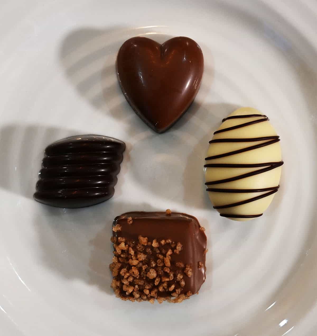 Image of the four different chocolates served on a white plate so you can see each flavor up close.