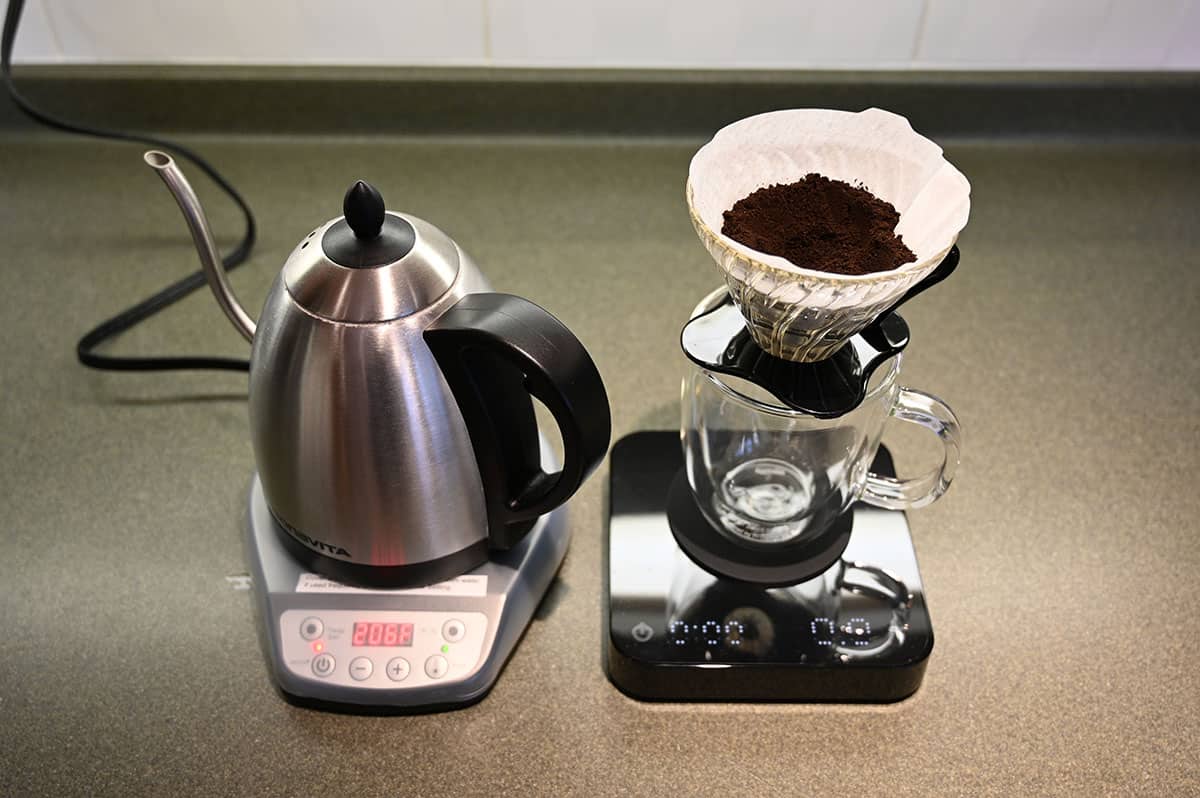 Image of a kettle and a kitchen scale with coffee beans in a filter on top the kitchen scale, ready to brew a coffee.