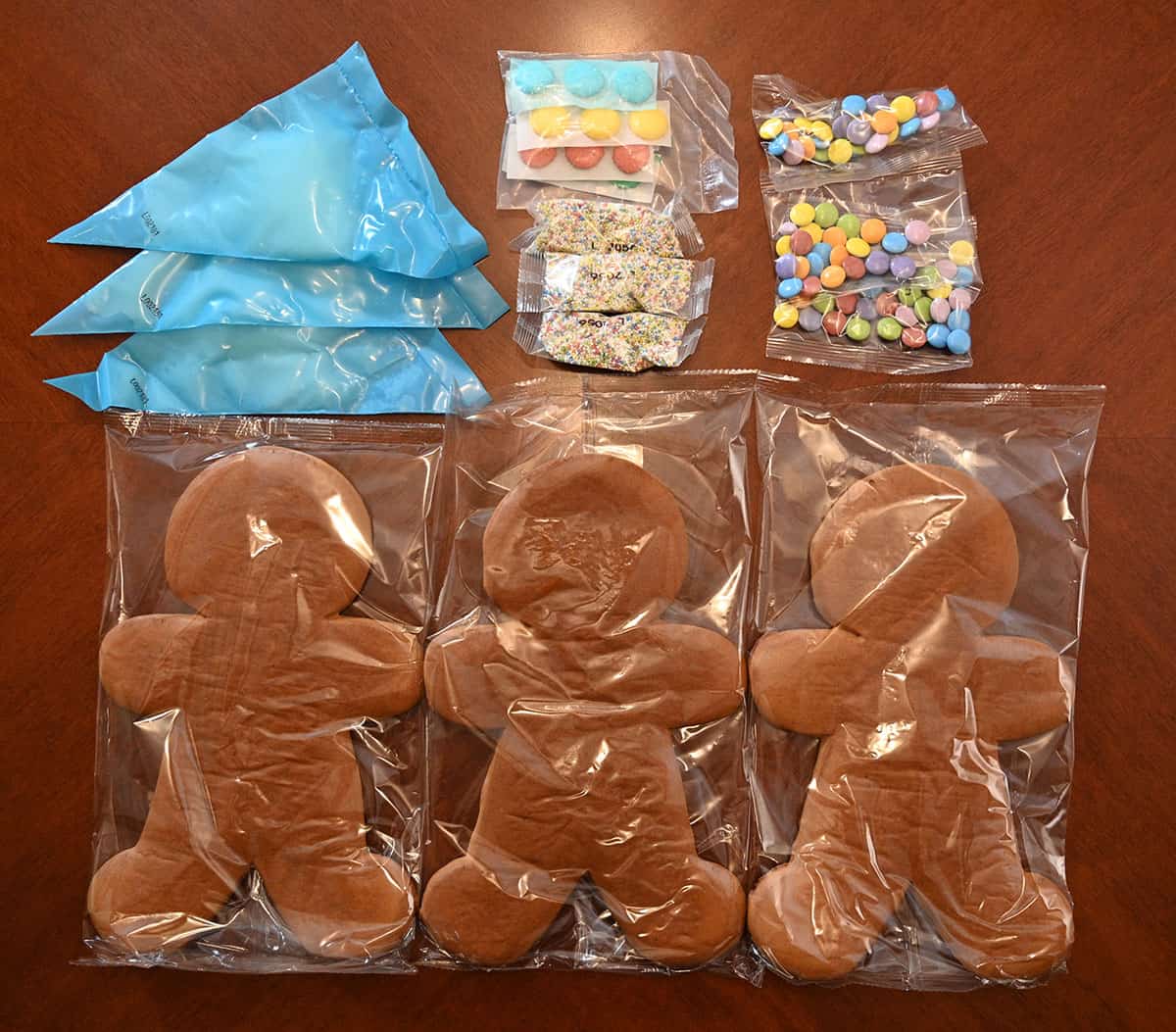 Image of all the contents in the box, icing, sprinkles, candy and three giant ginger people.