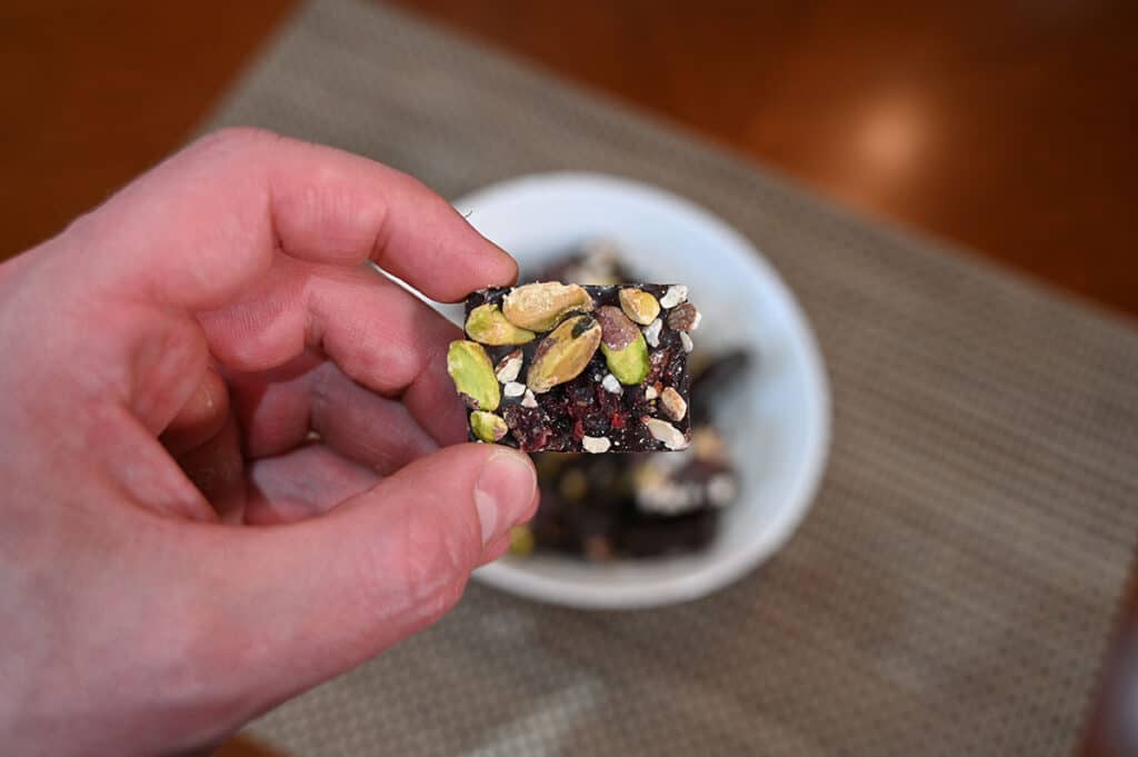 Closeup image of a hand holding one Jojo's Dark Chocolate Bite.