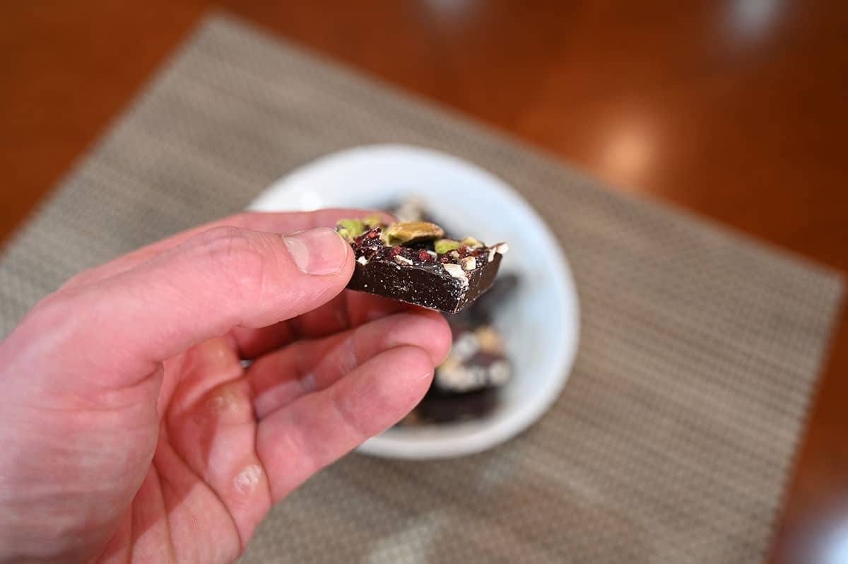 Closeup image of a hand holding one Jojo's Dark Chocolate Bite, side view image.