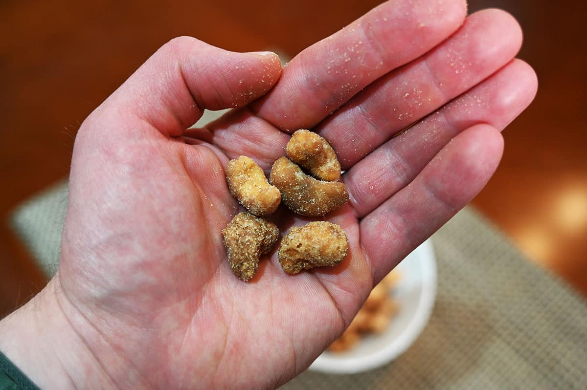 Image of a hand holding five butter toffee cashews.