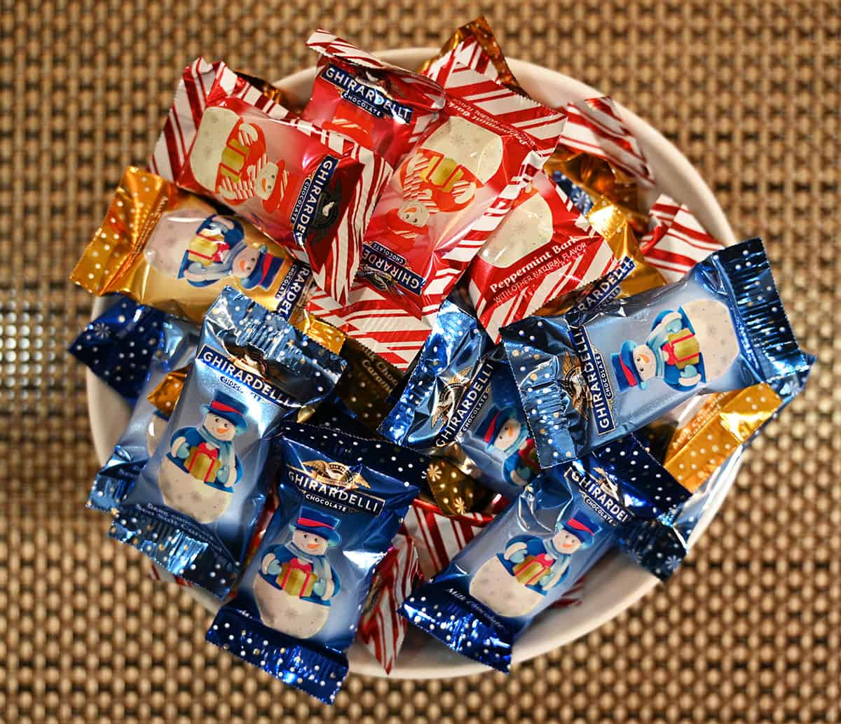 Top down image of a bowl full of Ghirardelli snowmen in their individual packaging.