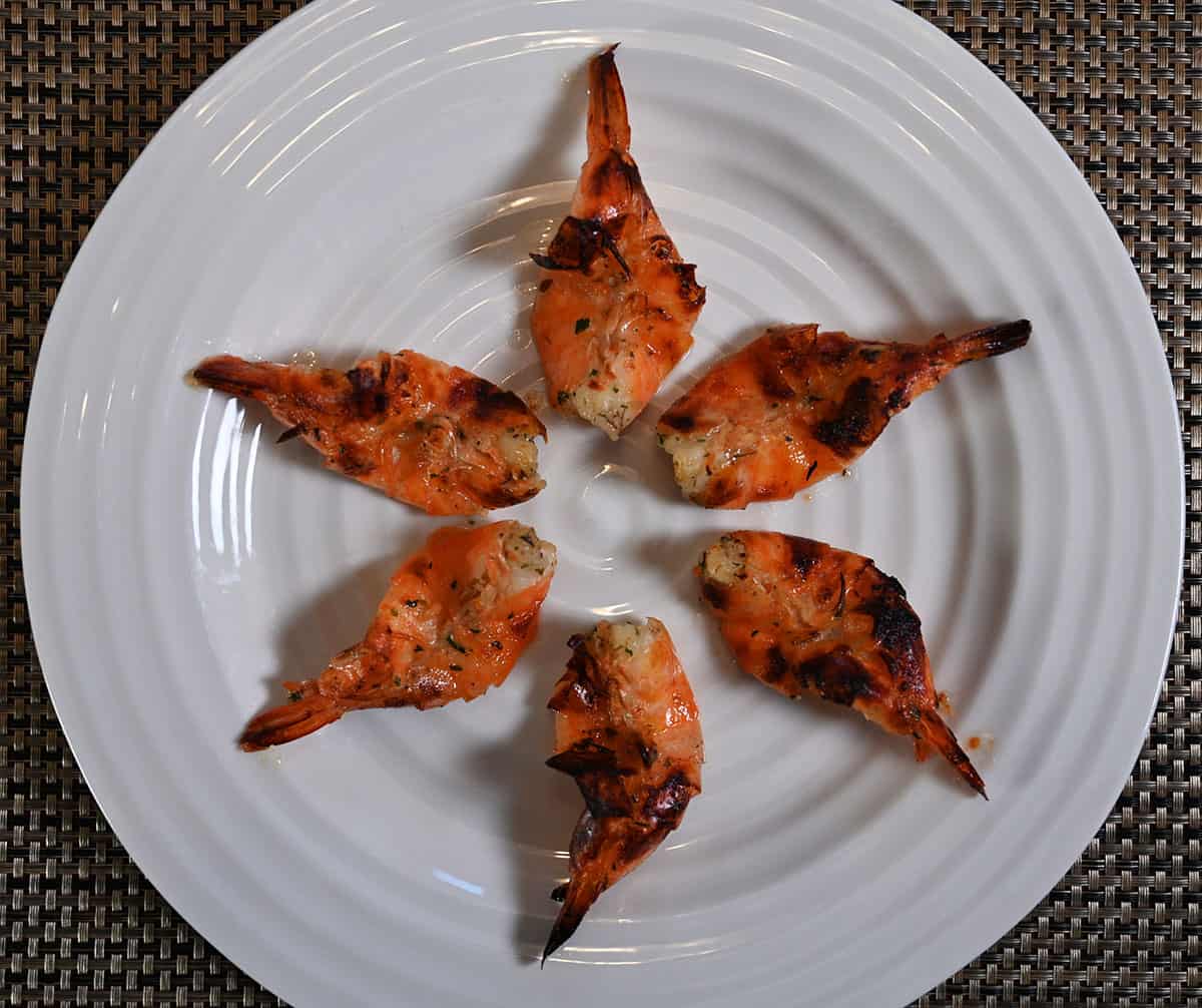 Top down image of a white plate with six cooked shrimp on it.