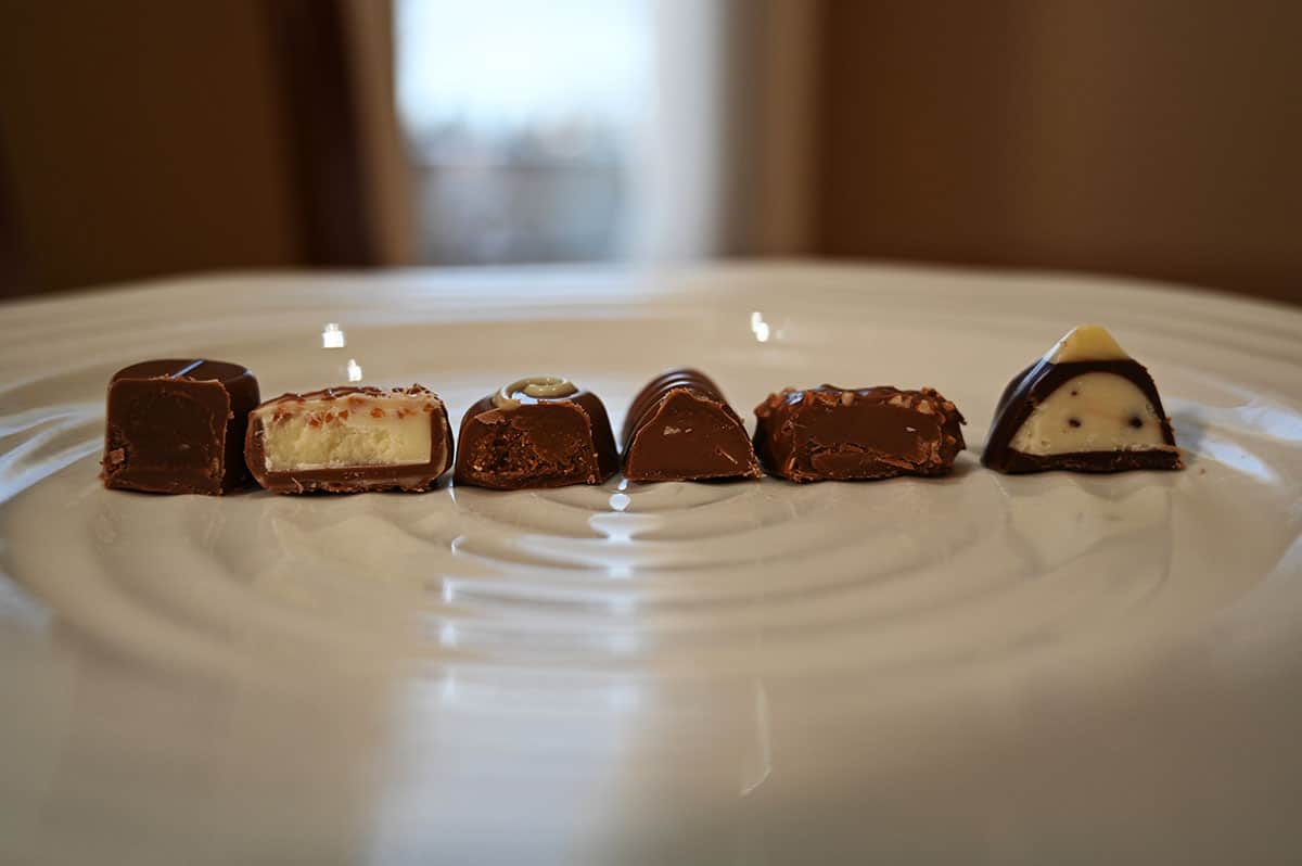 Image of six chocolates on a white plate cut in half so you can see the center of each chocolate, side view image.