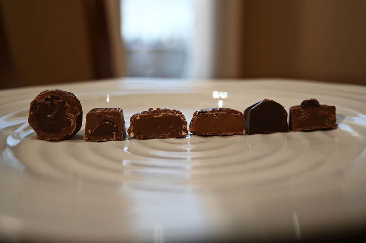 Image of six chocolates on a white plate cut in half so you can see the center of each chocolate, side view image.