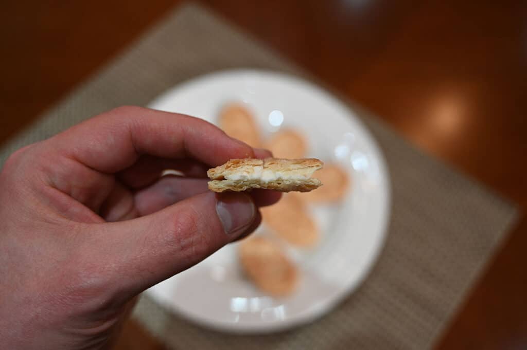 Image of a hand holding one Danish puff pastry with a bite taken out of it so you can see the center.