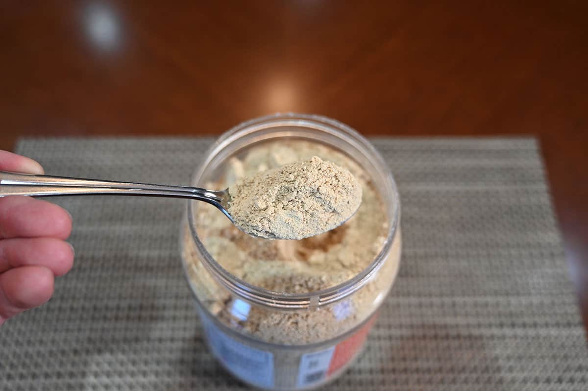 Top down image of the container of powdered peanut butter open with a spoonful overtop. 