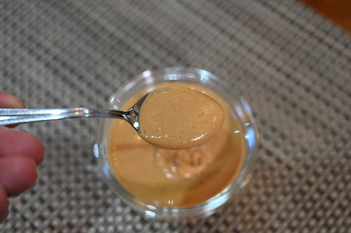 Top down image of the powdered peanut butter prepared in a bowl with a spoon over top showing what the prepared peanut butter looks like.