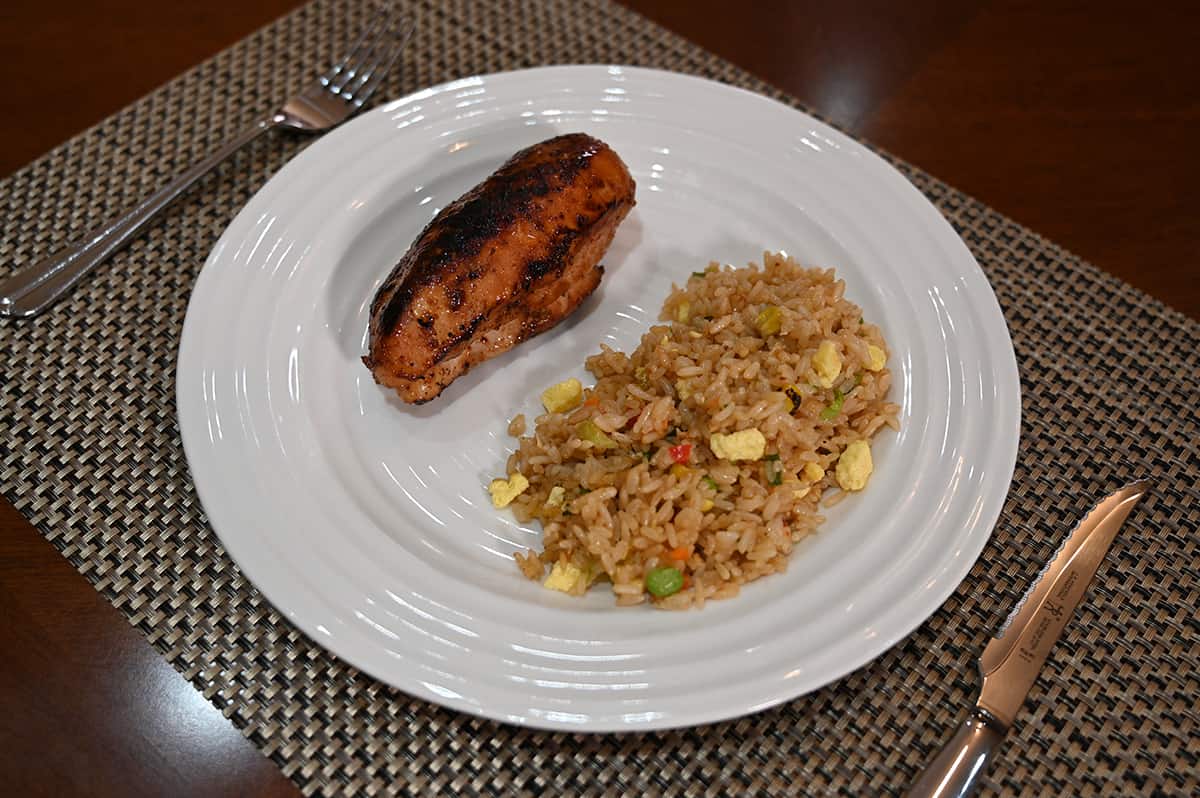 Side view image of a plate with chicken and vegetable fried rice on it.
