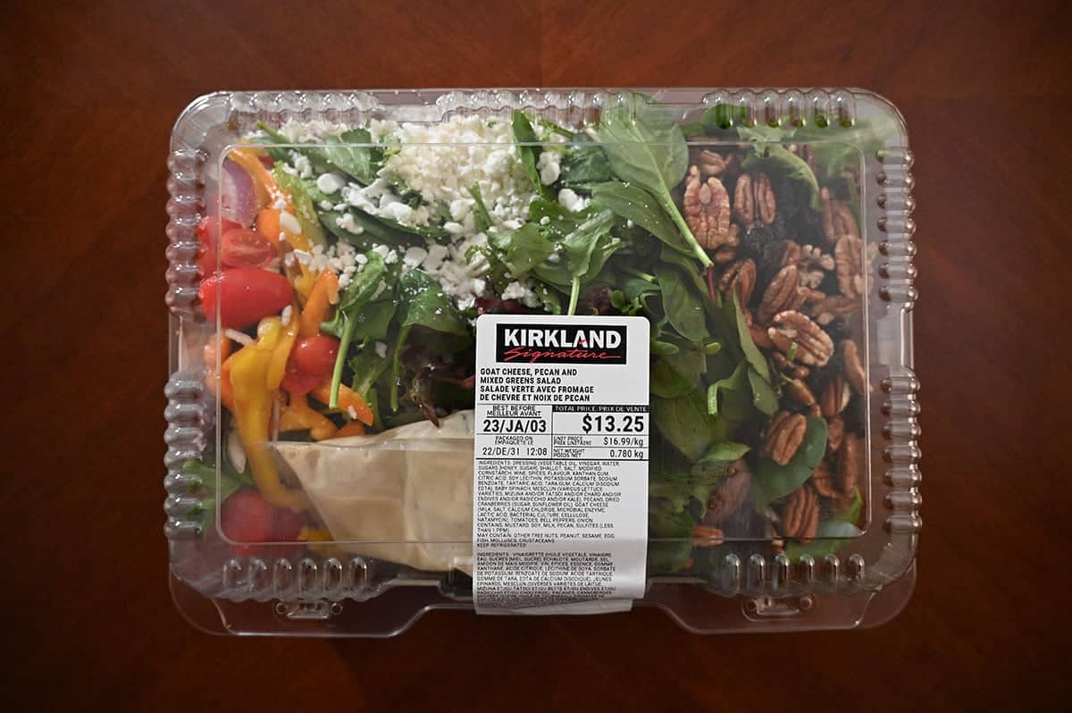 Top down image of the salad in the plastic container before opening it, sitting on a table.