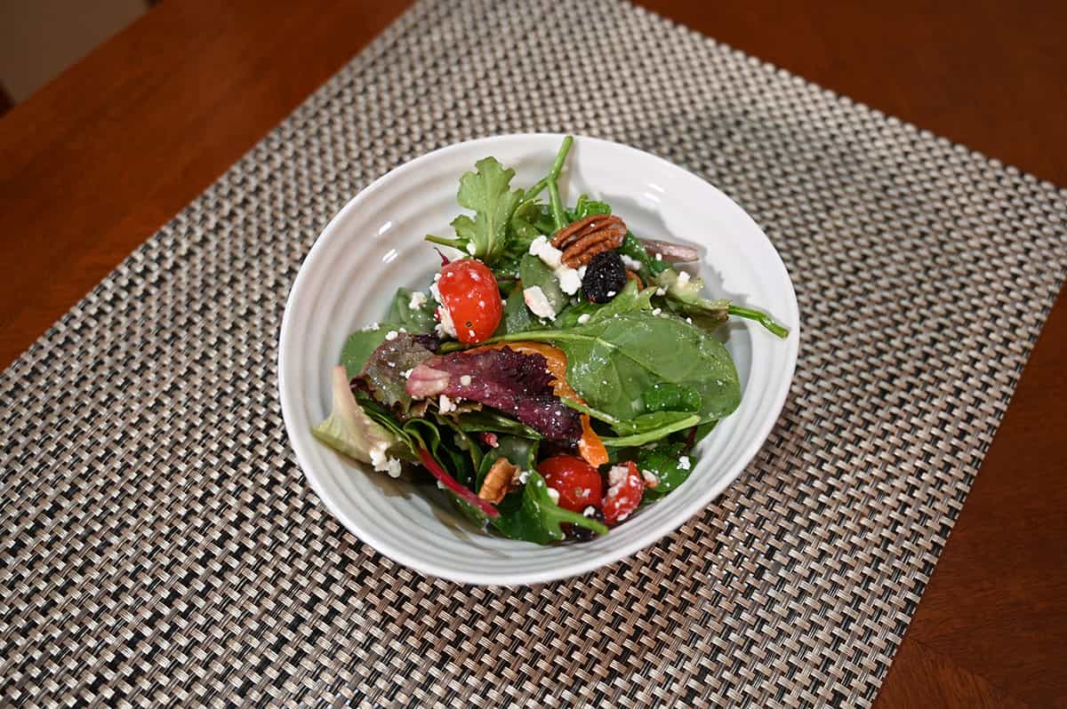 Image of a white bowl with a serving of salad in it sitting on a table.