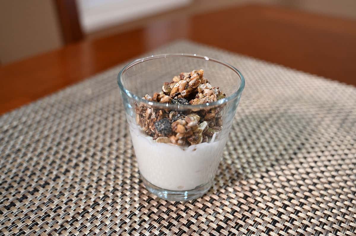 Closeup image of a glass cup with yogurt and the granola sprinkled on top. 
