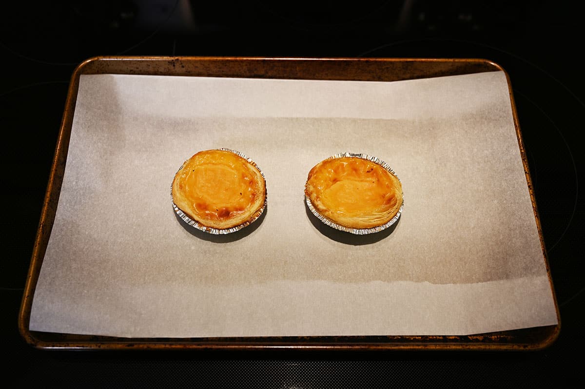 Image of two tarts on a baking tray lined with parchment paper after being baked in the oven.