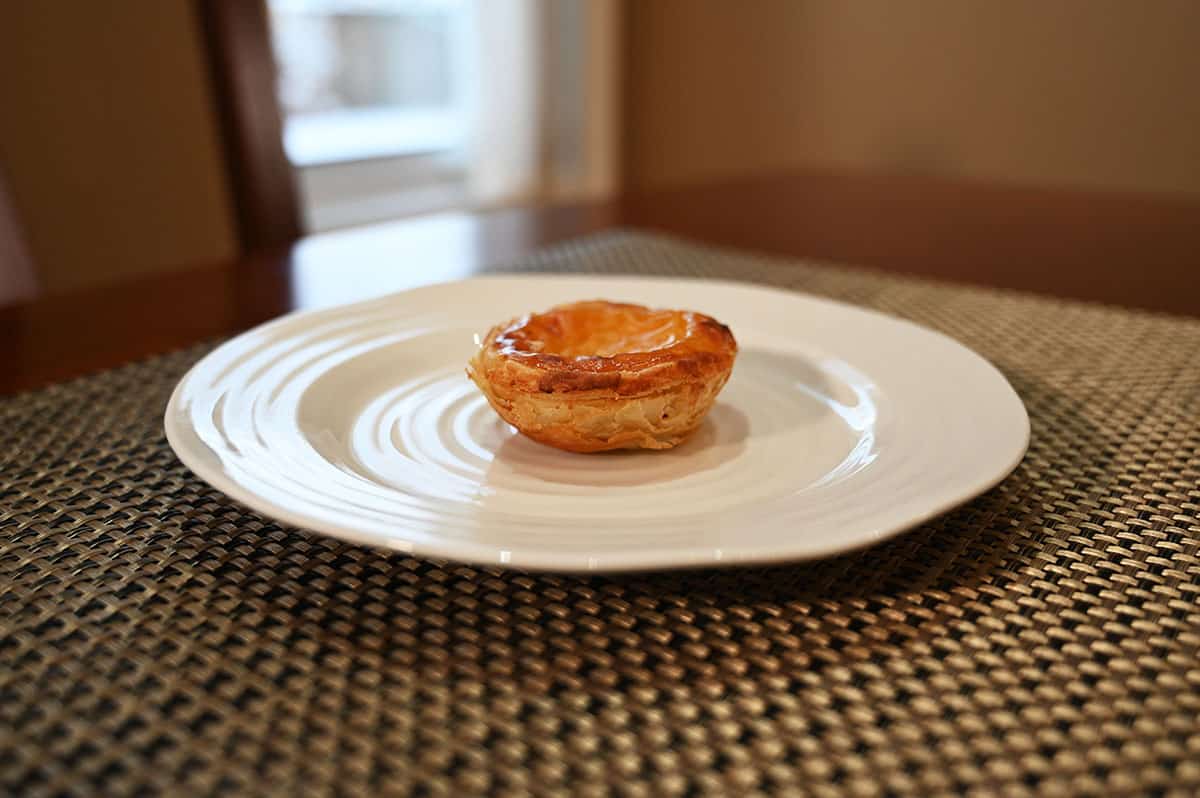 Side view image of a custard tart served on a white plate.