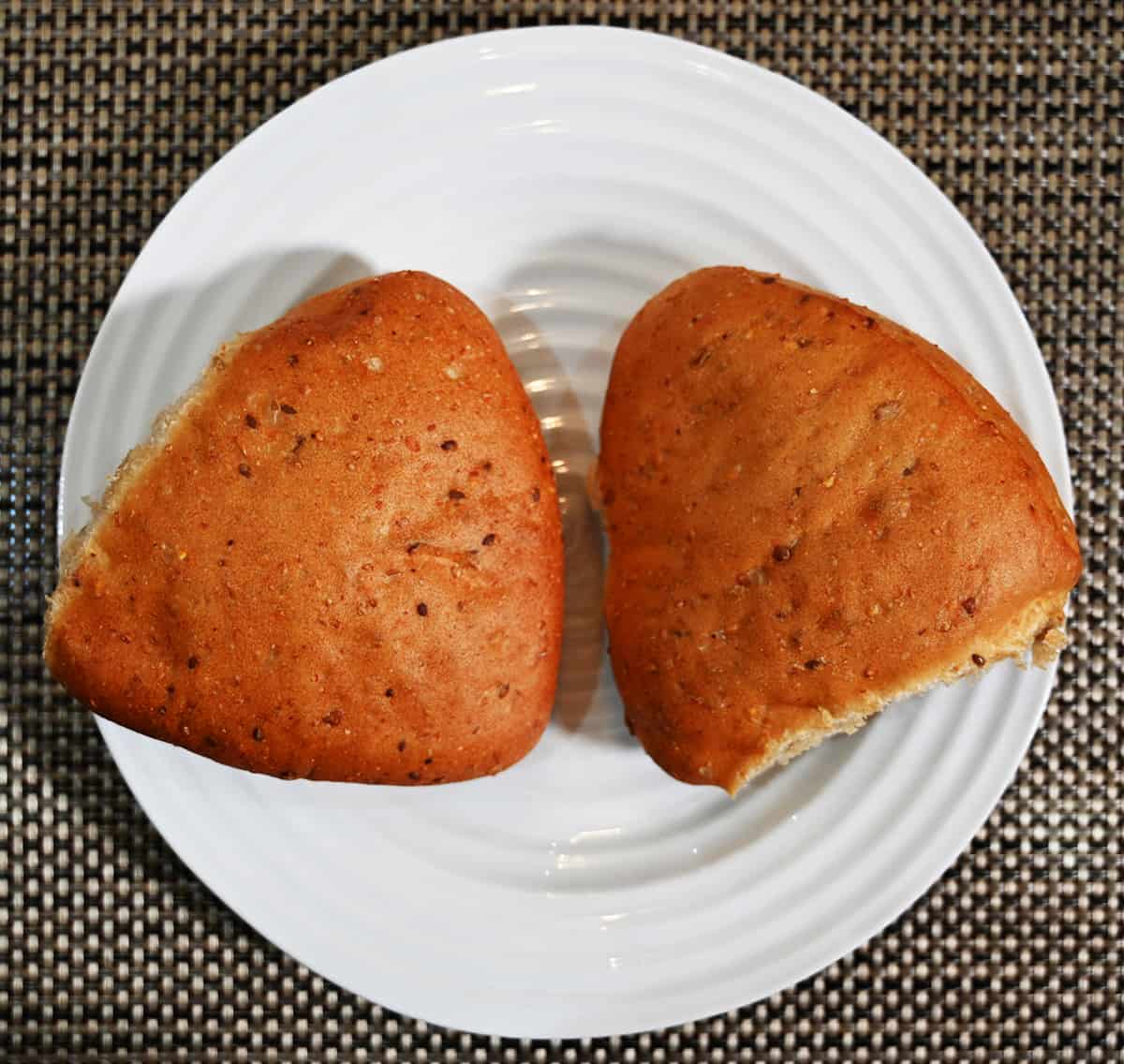 Top down image of two 9 grain ciabatta buns sitting on a white plate.