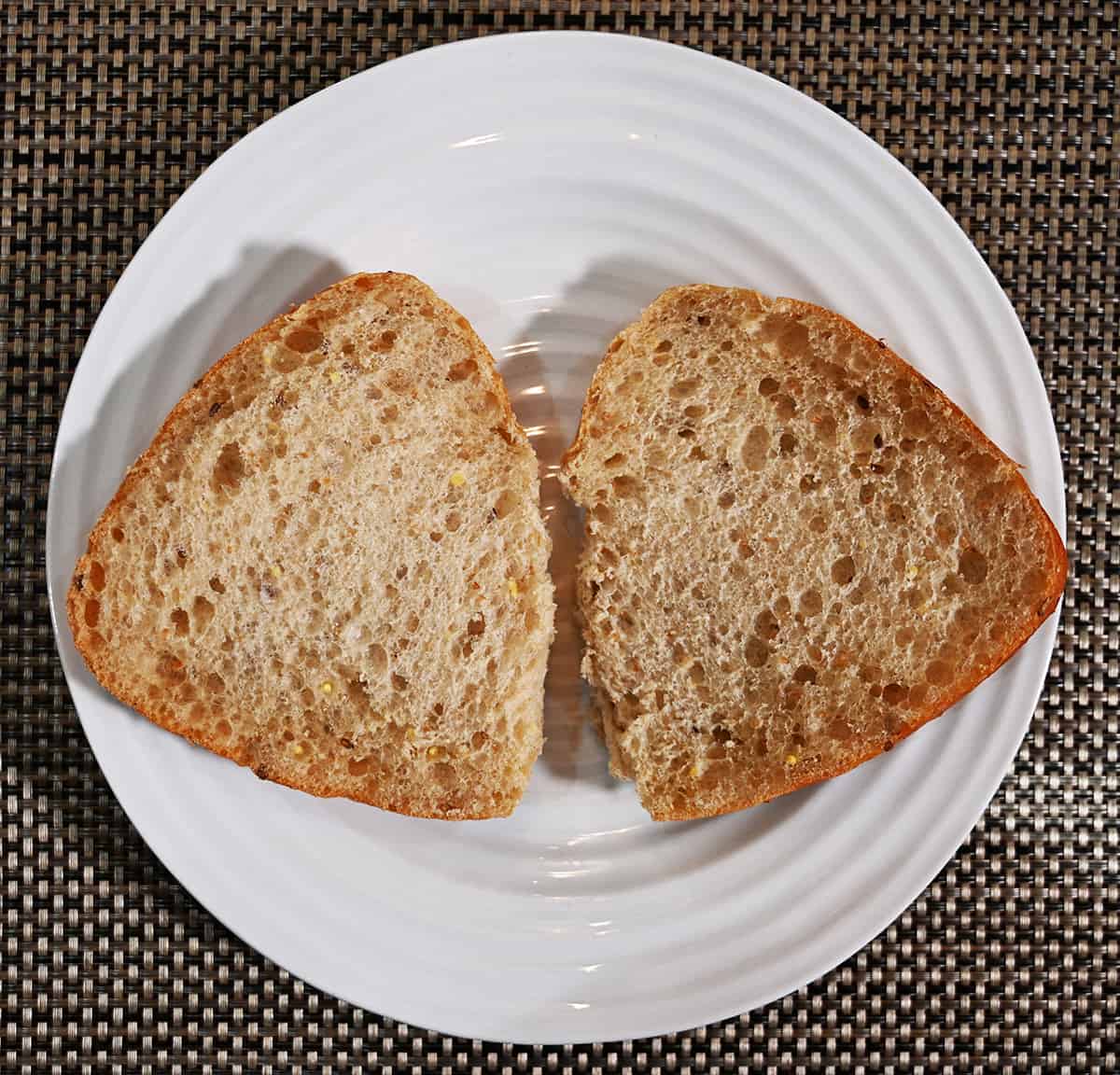 Top down image of a 9 grain ciabatta bun cut in half and served open on a plate so you can see the center.