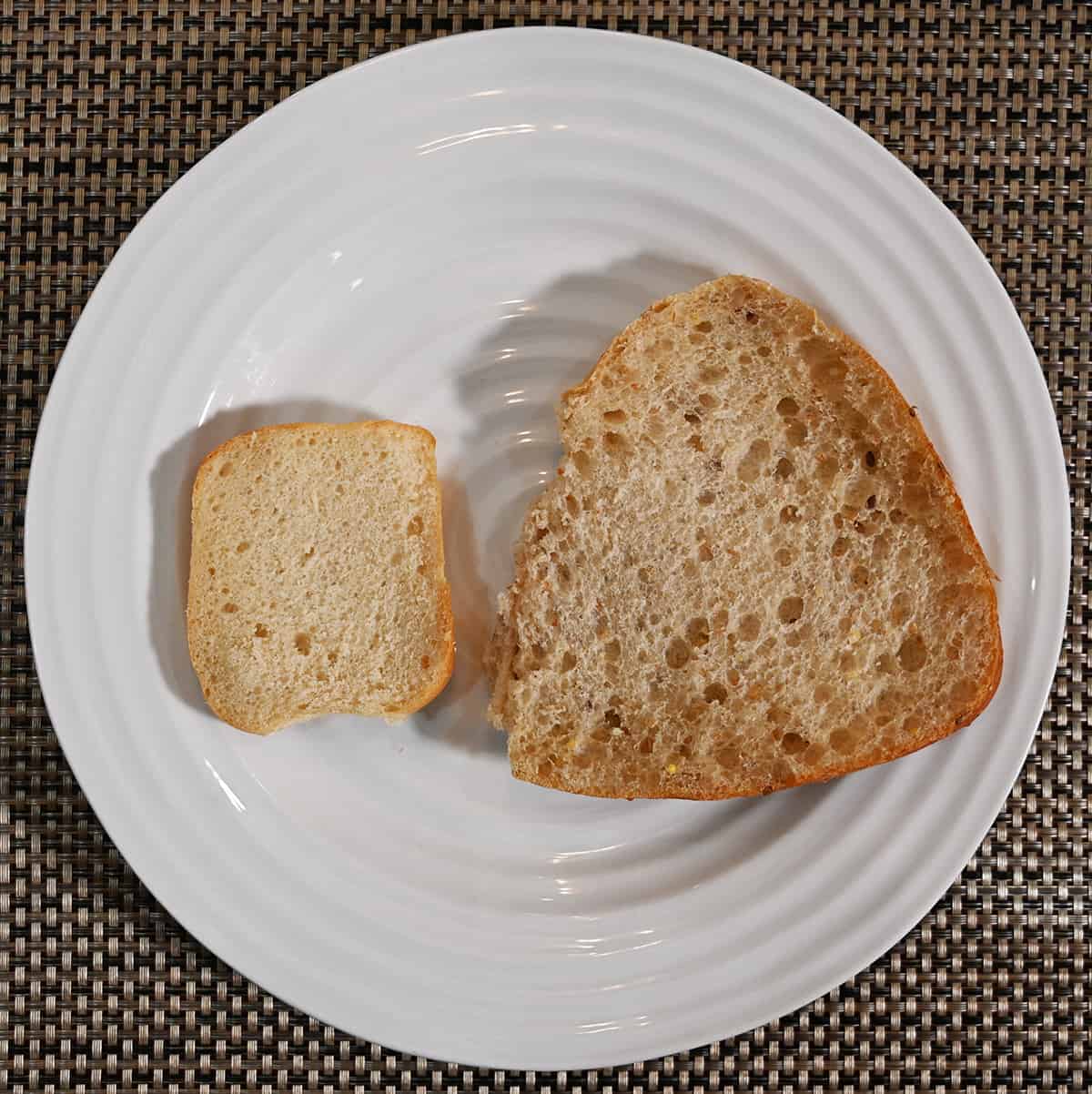 Top down image of one half of an Italian ciabatta beside one half of a 9 grain ciabatta bun on a plate so you can see the inside of the buns.