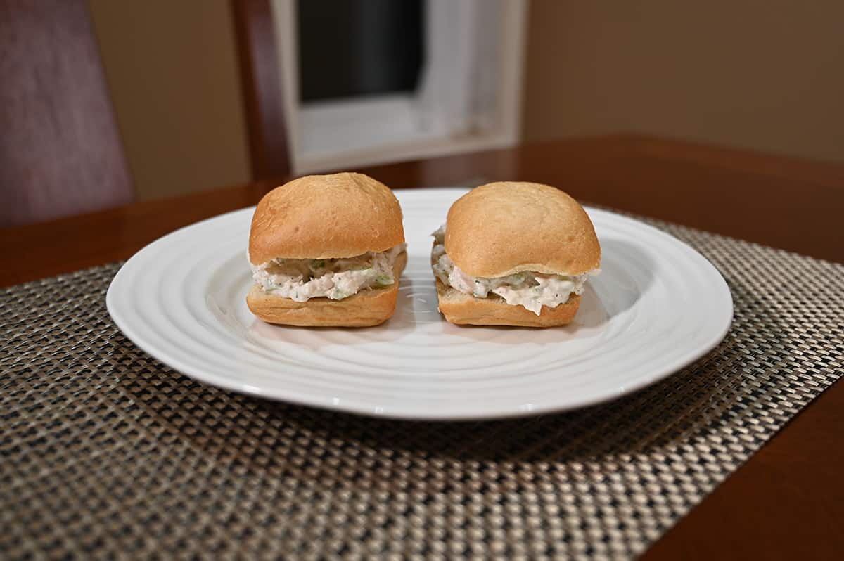 Side view image of two Italian ciabatta buns from Costco filled with chicken salad on a white plate to make sandwiches.