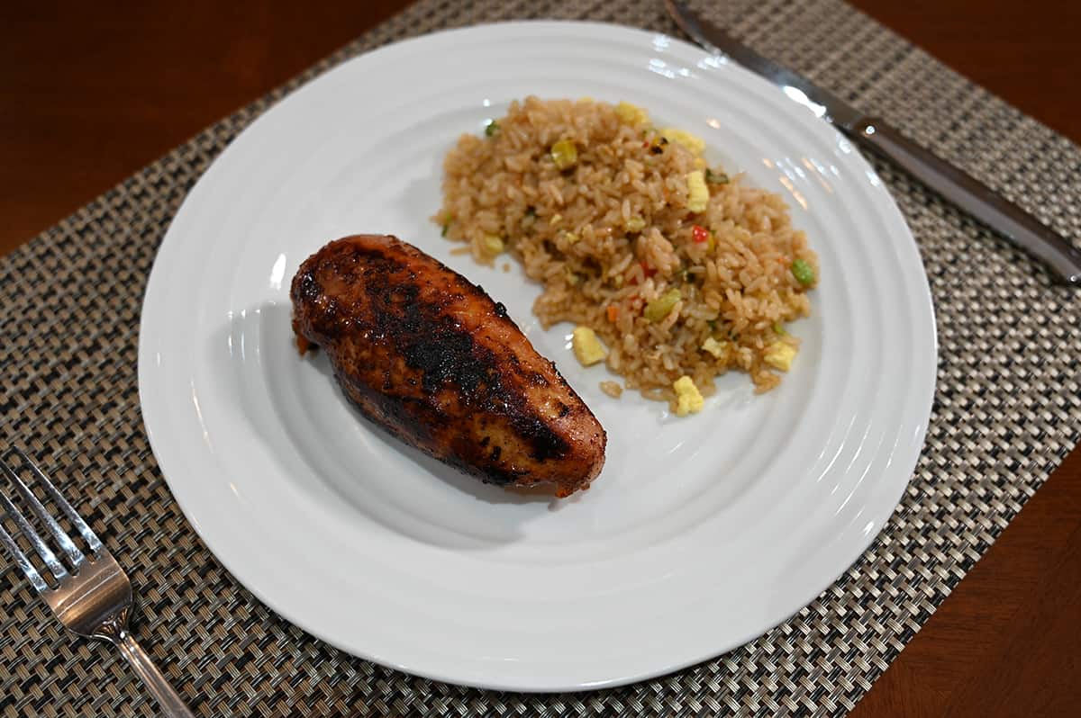 Image of a cooked chicken breast using the marinade beside vegetable fried rice on a white plate.