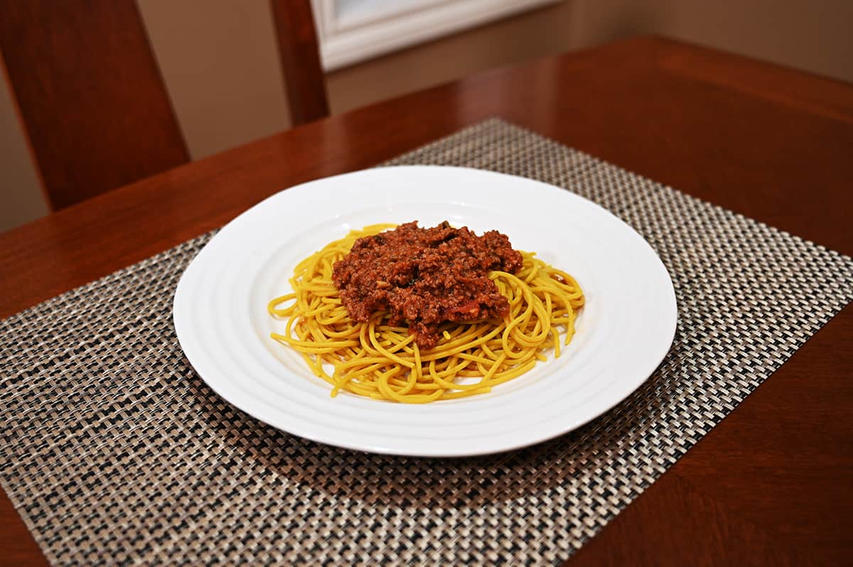 Side view image of the prepared spagehtti with a red meat sauce served on a white plate.