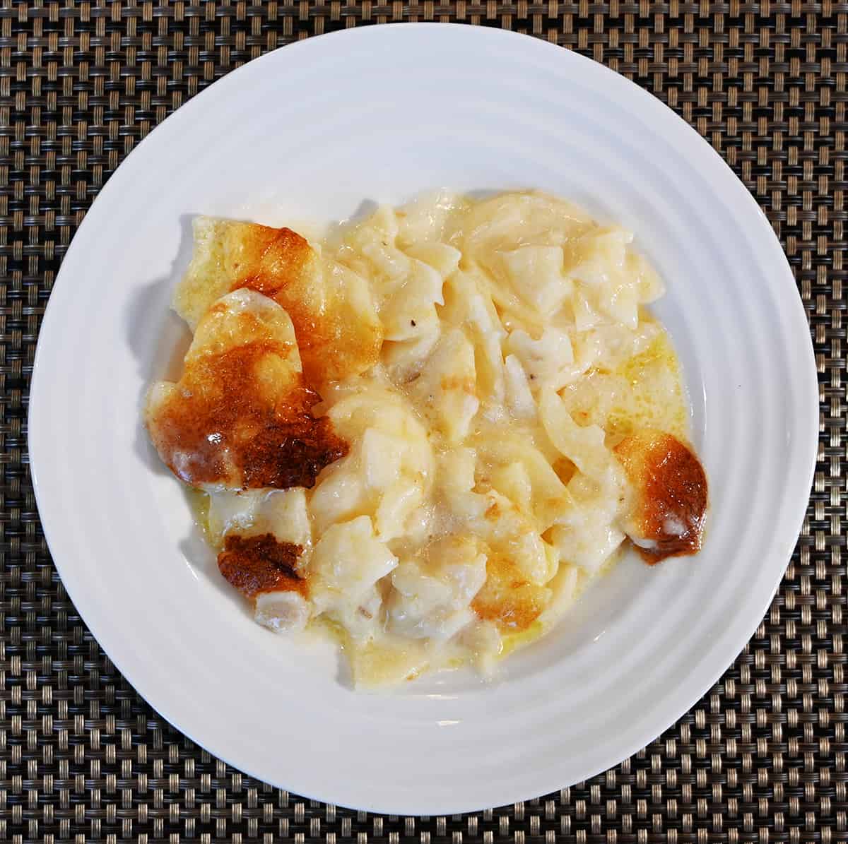 Top down image of a white plate with potatoes au gratin served on it.