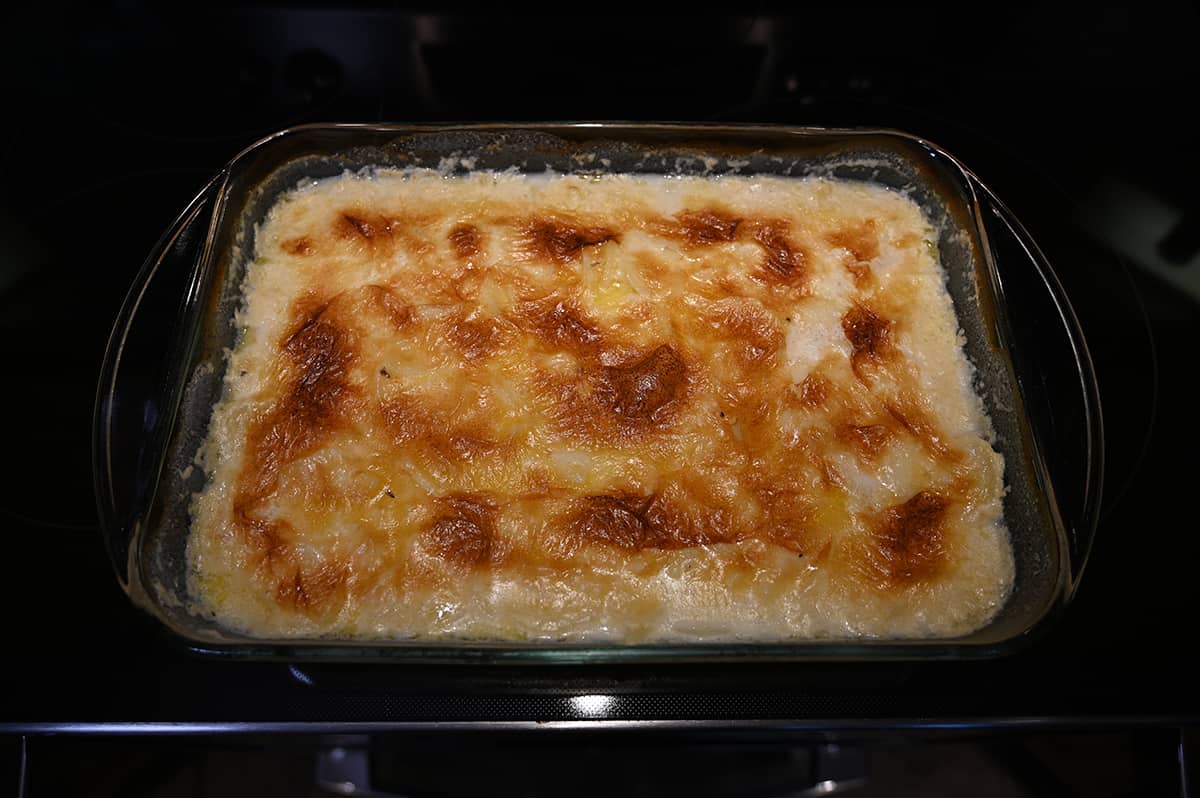 Image of a casserole dish with prepared au gratin potatoes sitting on a stovetop.