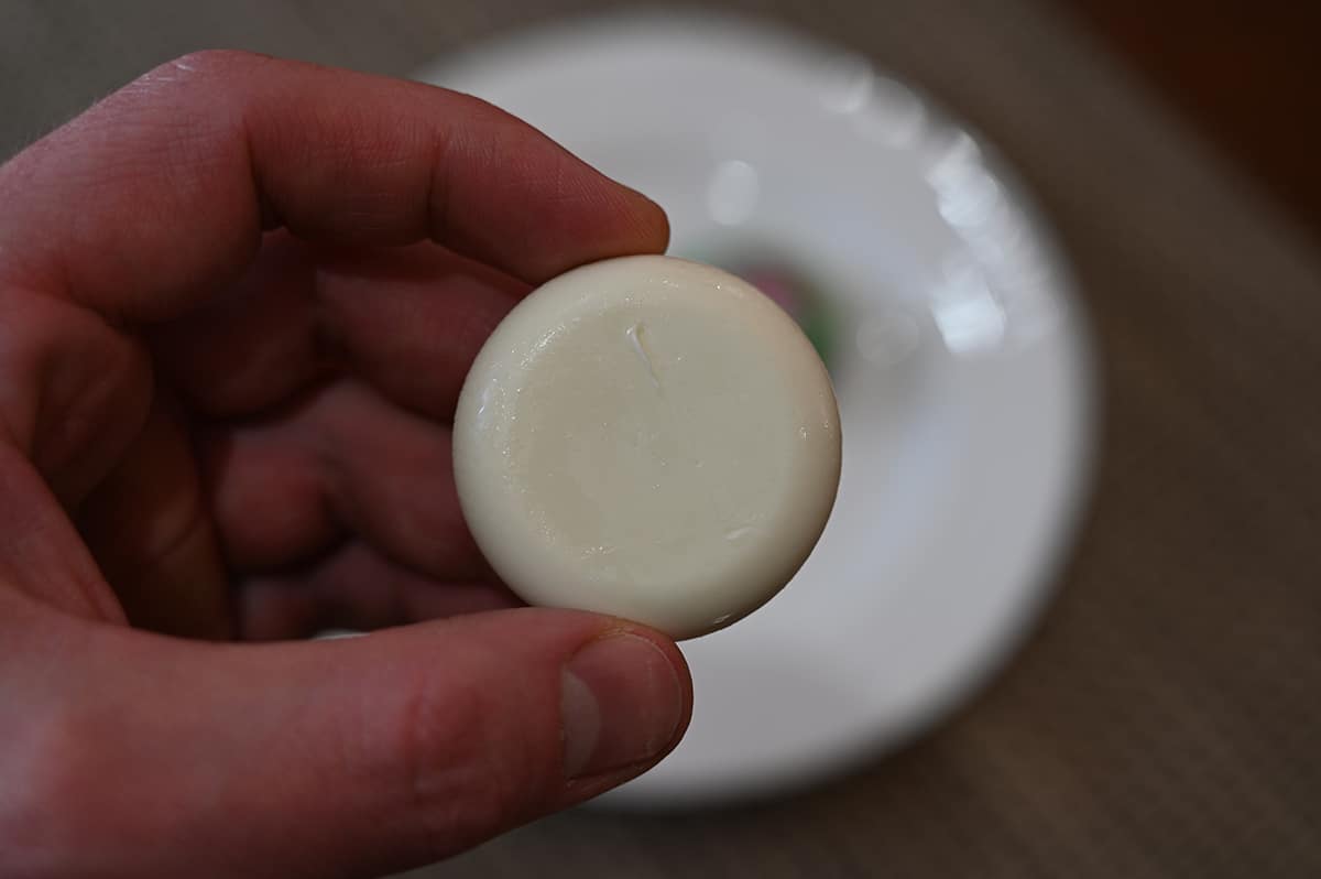 Closeup image of a hand holding one plant-based Babybel wheel. 