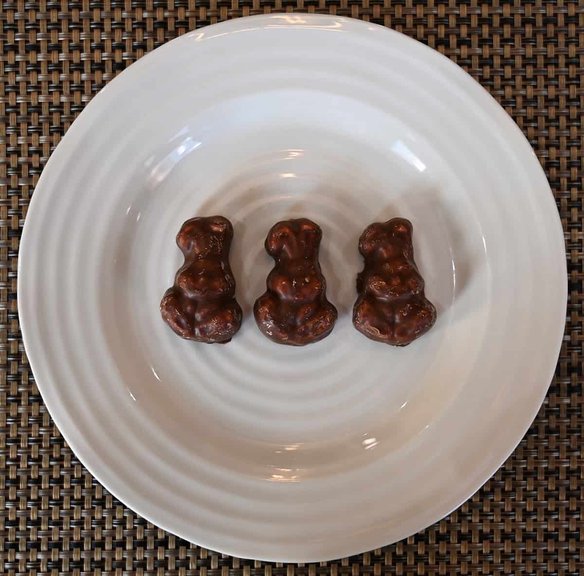 Top down image of three marshmallow chocolate bunnies sitting on a white plate.