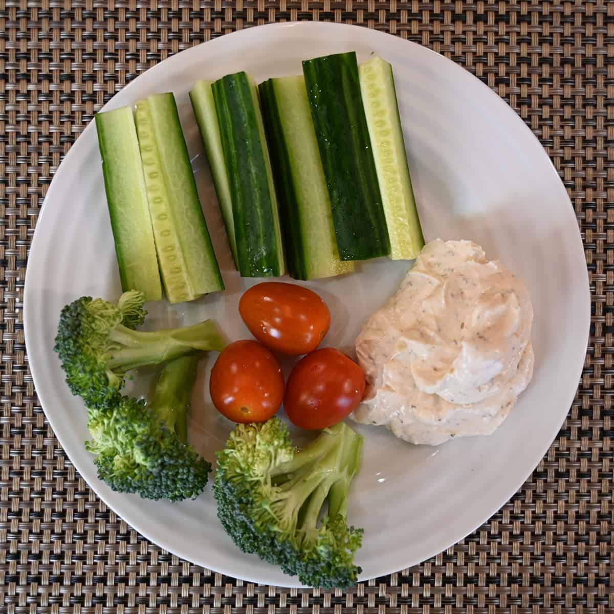 Top down image of a plate of vegetables with dip beside them.
