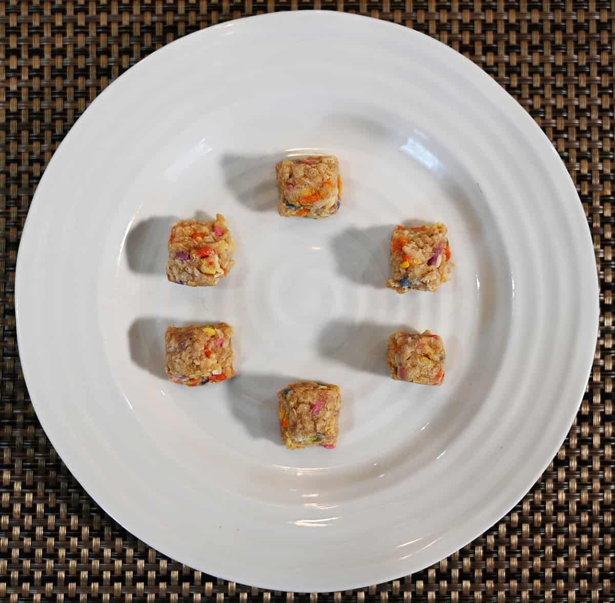 Top down image of six birthday cake flavor hunks on a white plate in a circular pattern.