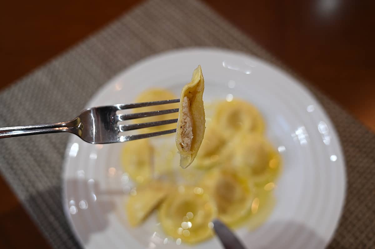 Closeup image of one ravioli on a fork cut in half so you can see the filling inside.