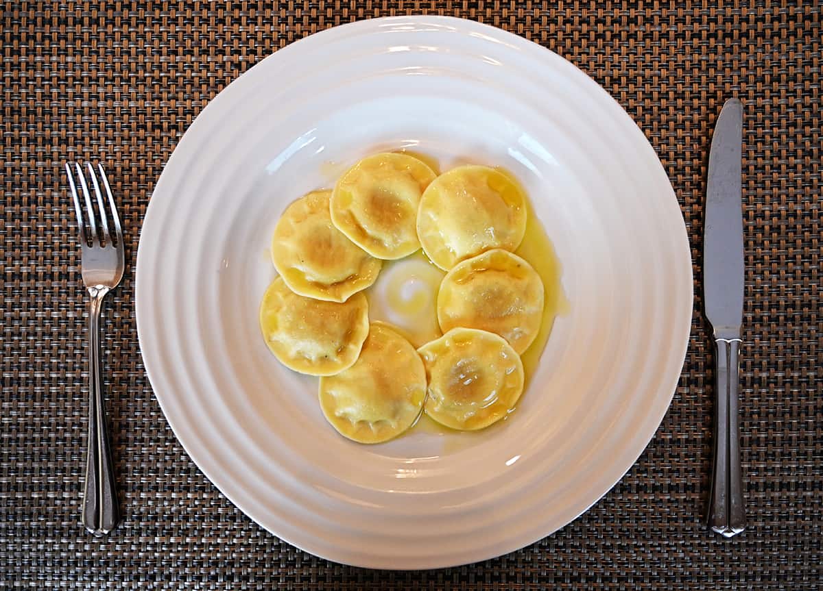 Top down image of a plate of prepared ravioli served in a circle with a drizzle of olive oil on top.