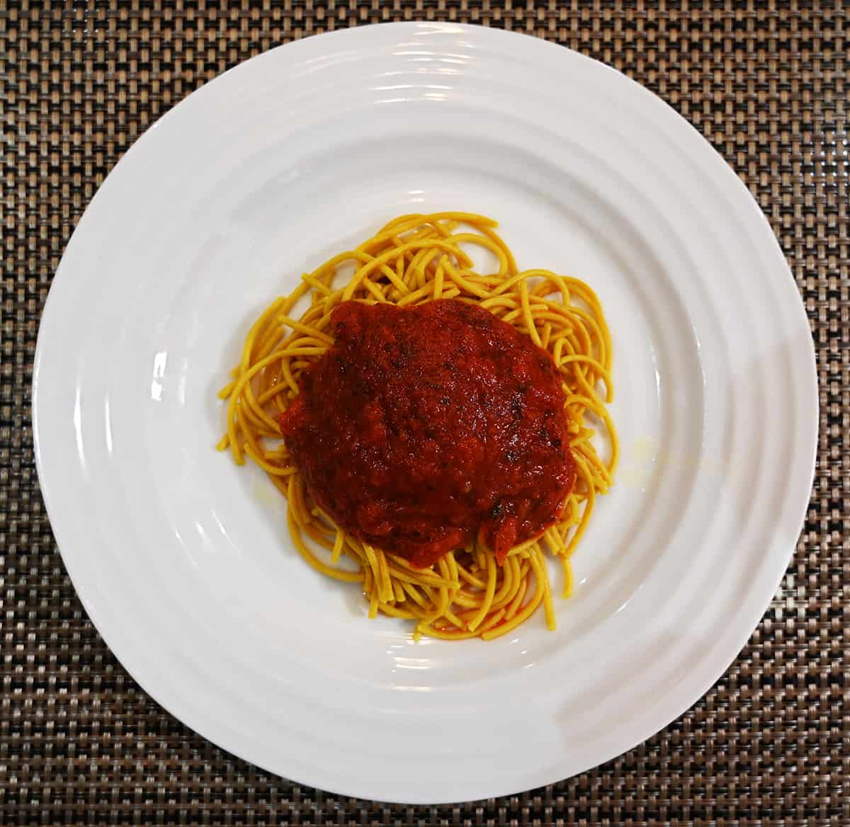 Top down image of a white plate with prepared spaghetti with sauce on top.
