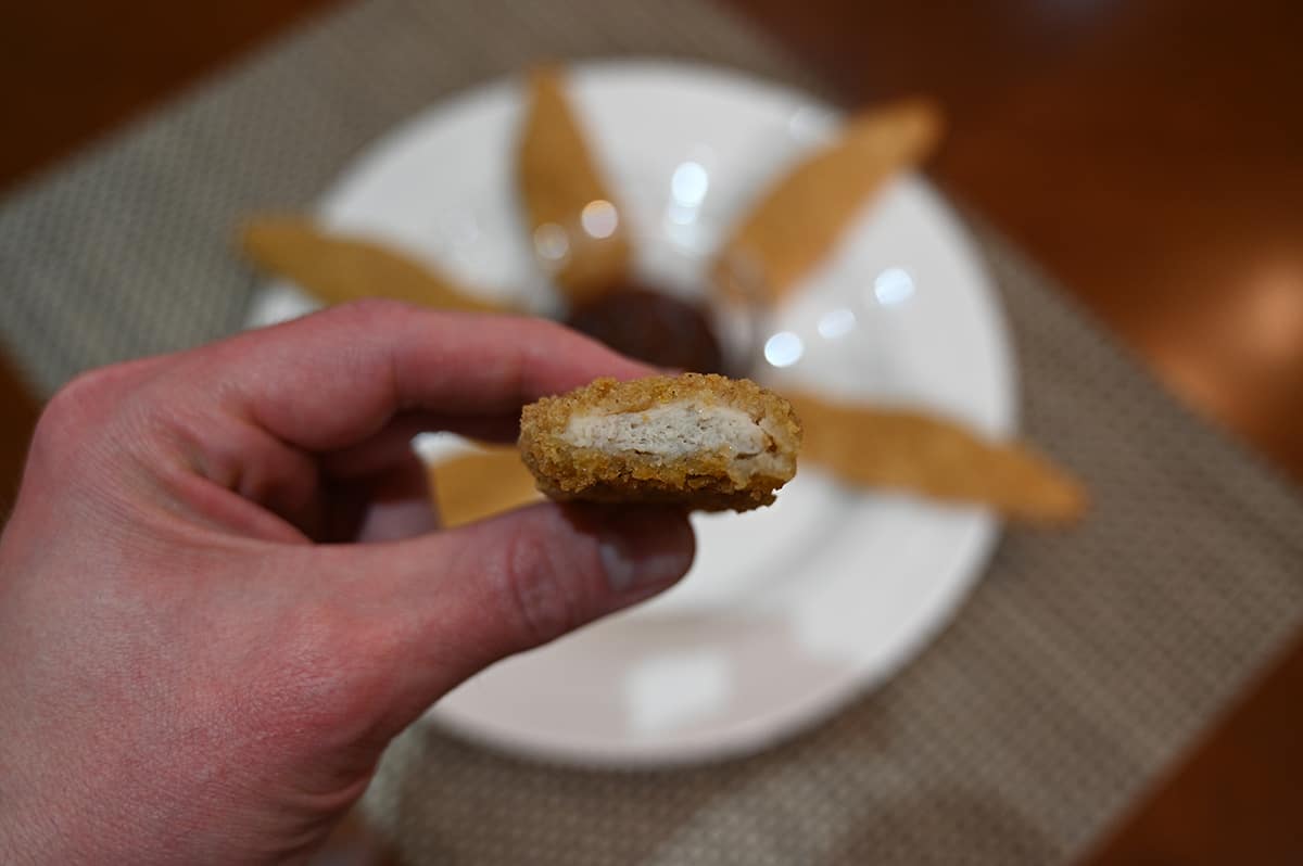 Closeup image of a chicken strip with a bite taken out of it so you can see the center.