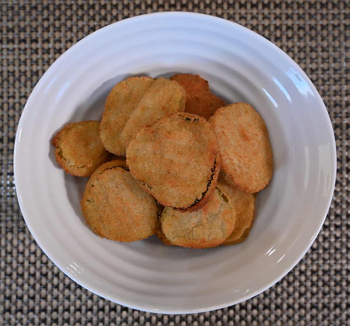 Top down of the breaded dill pickle chips cooked and served in a white bowl.