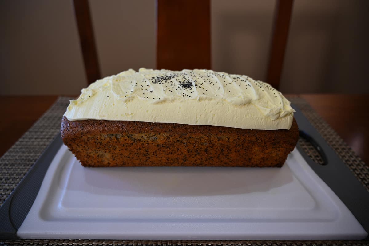 Side image of the lemon poppyseed loaf out of the container and sitting on a cutting board.