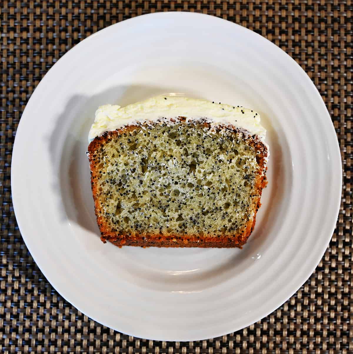 Top down image of one slice of lemon poppyseed loaf served on a white plate.