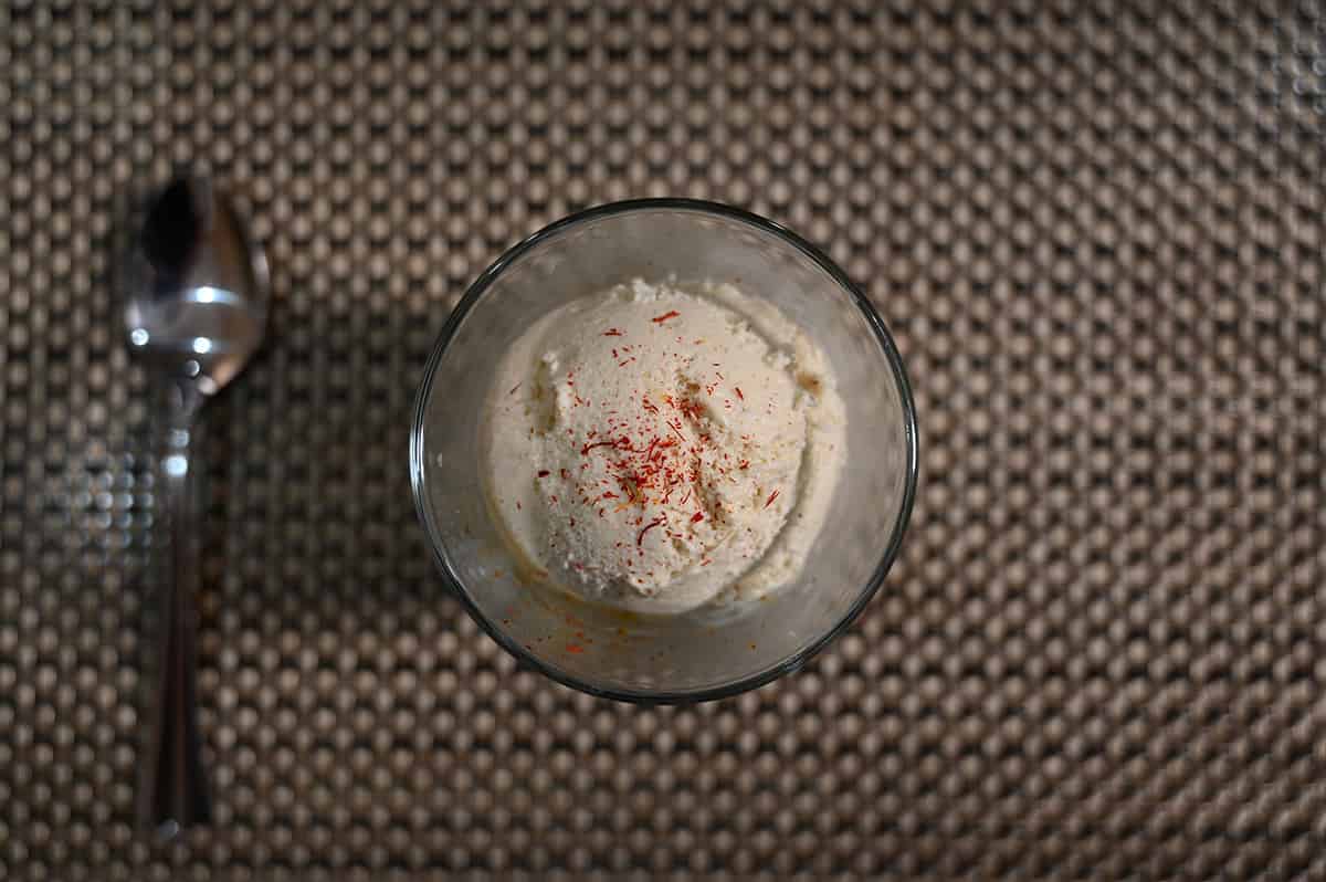 Top down image of a small cup of vanilla ice cream with saffron sprinkled on top.