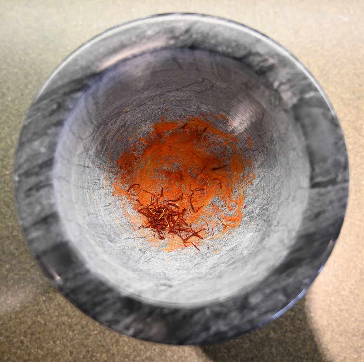 Top down image of ground saffron in a mortar.