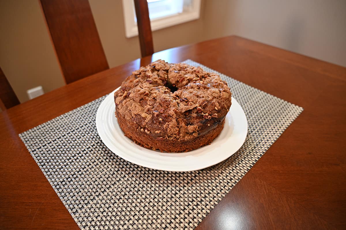 Side view image of the entire coffee cake served on a white plate and sitting on a dining table.