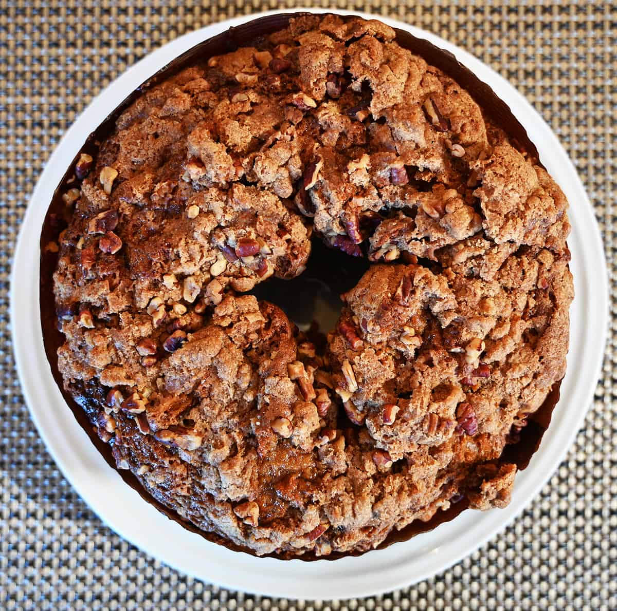 Top down image of the coffee cake ubnwrapped so you can see the top sprinkled with pecans. 