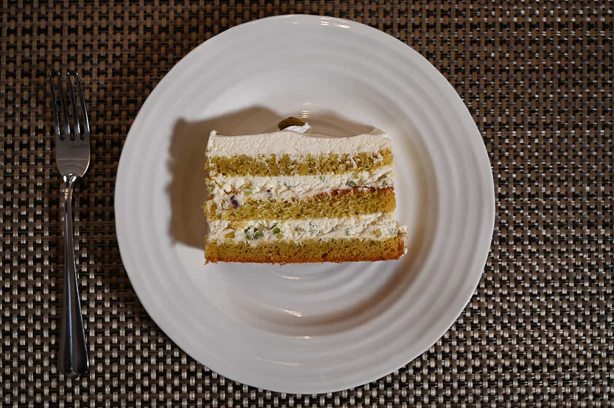 Top down image of one slice of the pistachio cake laying on its side on a white plate so you can see the layers.