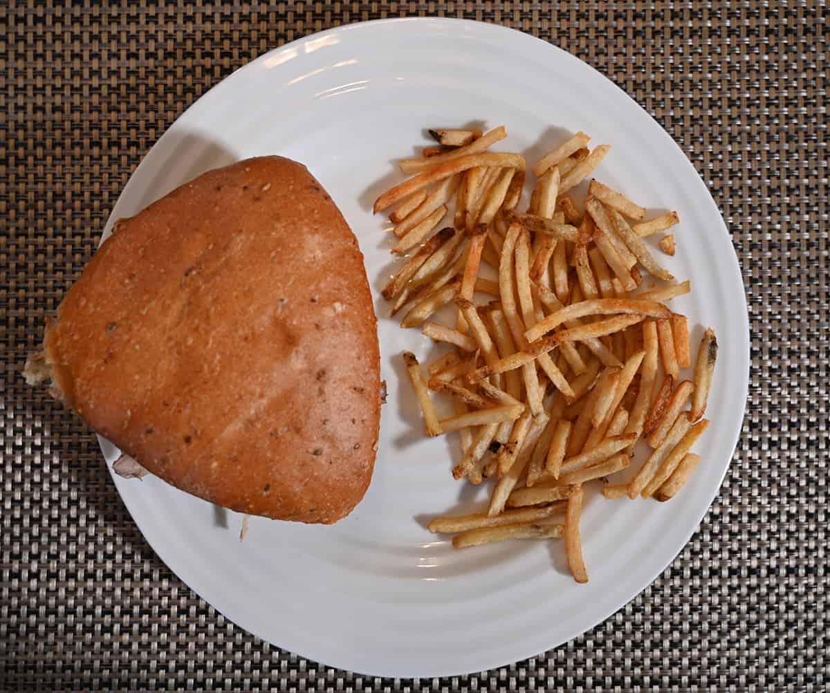 Top down image of a pulled pork sandwich served on a plate beside a sie of fries.
