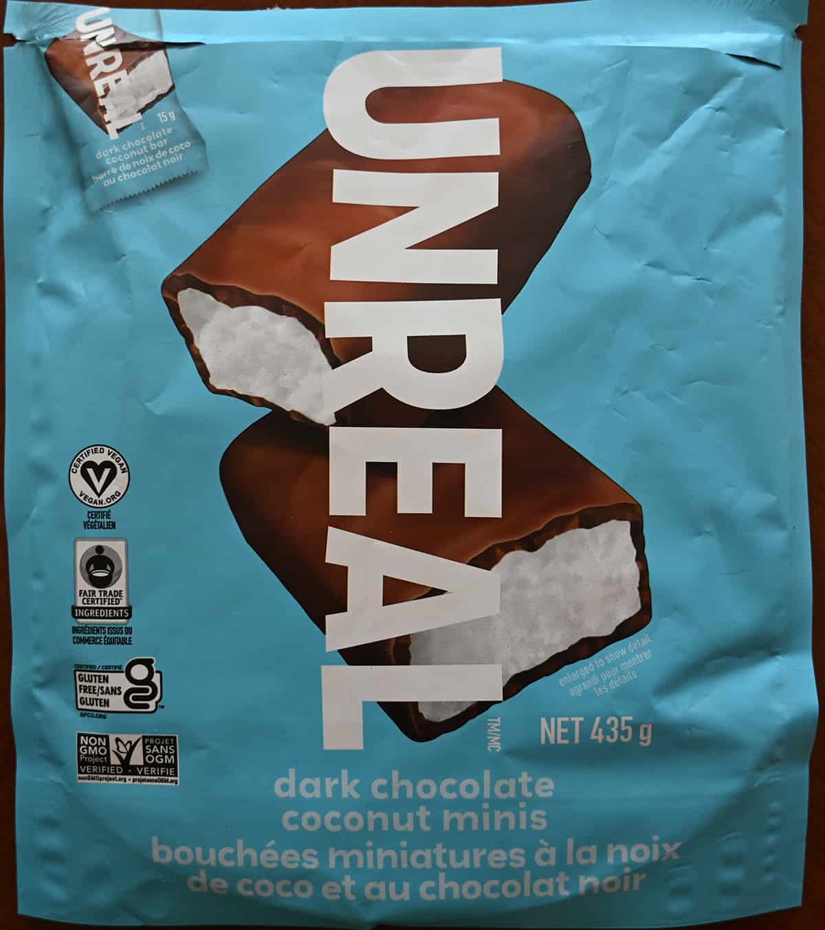 Closeup image of the front of the bag of dark chocolate coconut minis showing the weight of the bag and that they're fair trade certified and Non-GMO certified.