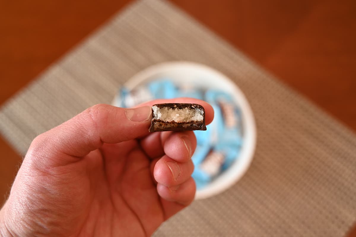 Image of a dark chocolate coconut bar unwrapped with a bite taken out of it so you can see the center.