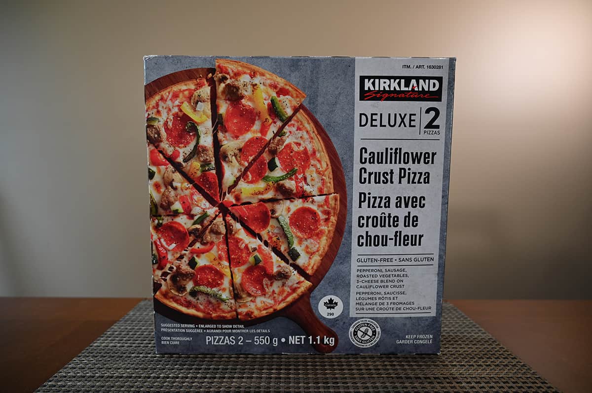 Image of the Costco Kirkland Signature Deluxe Cauliflower Crust Pizza box sitting upright on a table.