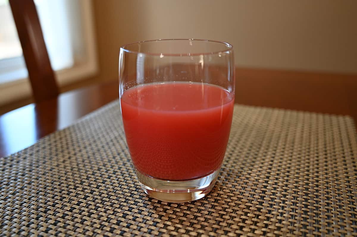 Closeup image of a clear glass full of guava juice.
