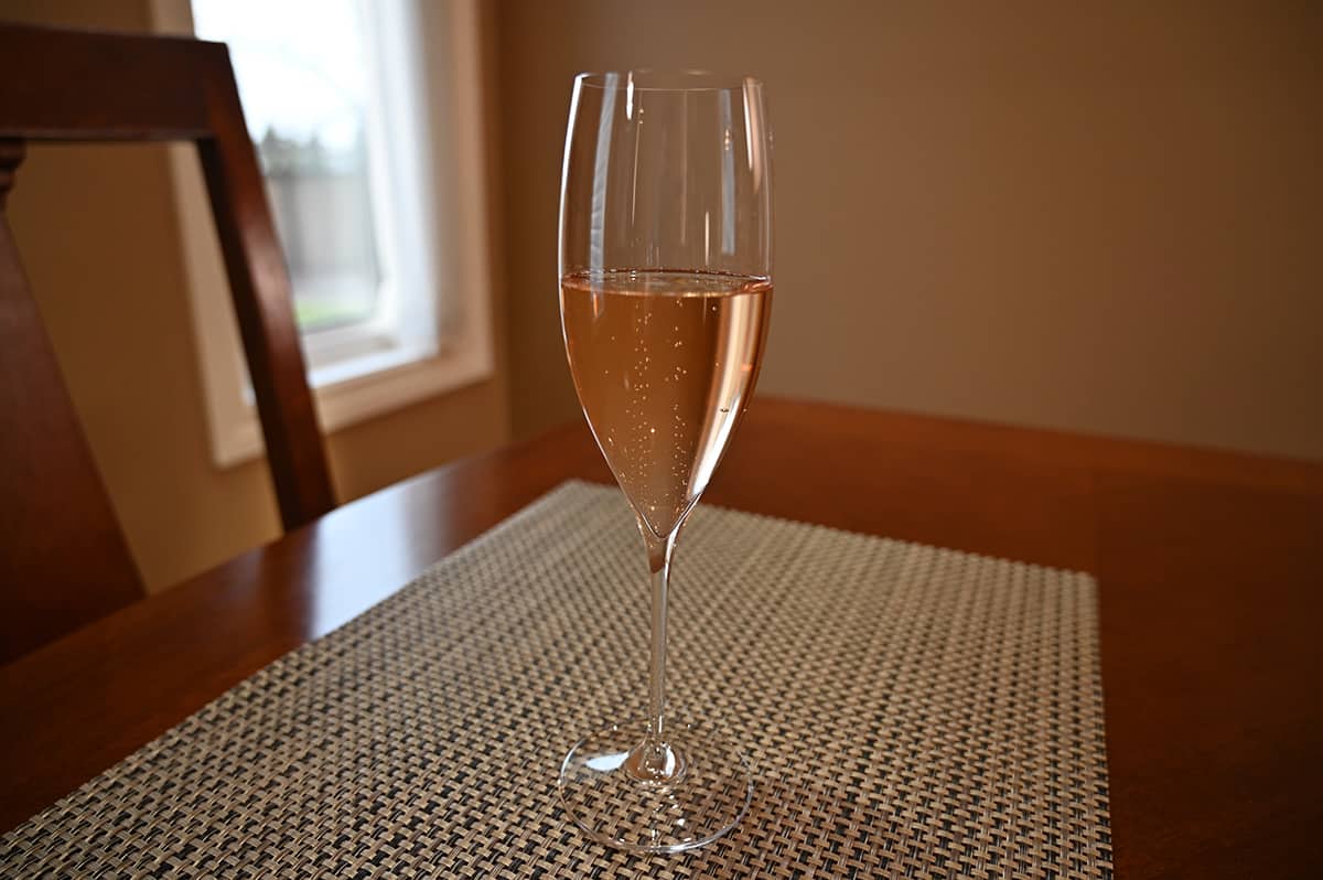 Image of one glass or prosecco poured and sitting on a dining table.