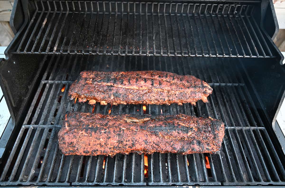 Image of two racks or ribs on a barbecue cooking. The ribs have a nice seared appearance.